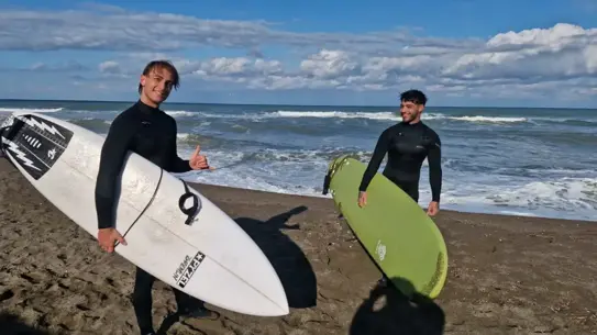 Denizde sörf yapanları izleyen gözlemciler