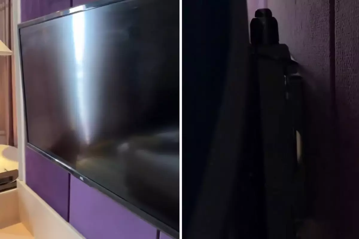 Otel odasında televizyonun arkasına bakan adam